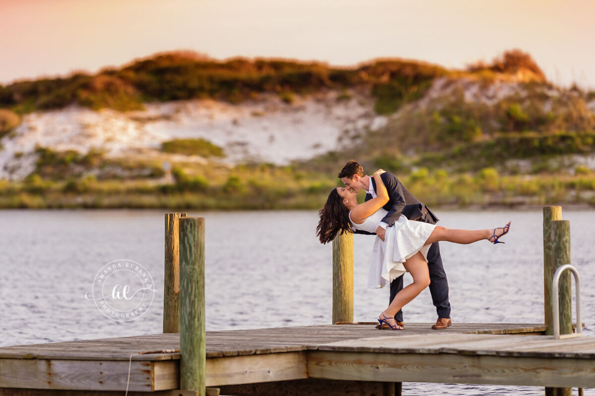 Destin engagement photographer captures dip kiss on wooden dock by the water