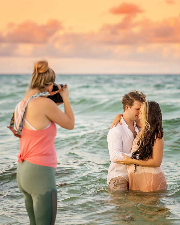 Destin photographer behind the scenes capturing engagement couple in surf at sunset