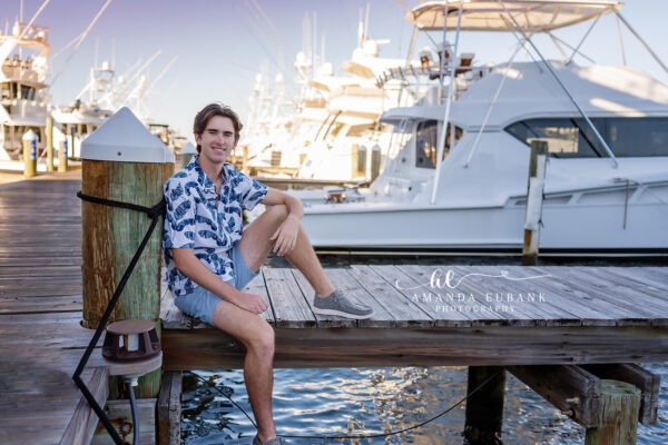 Destin senior photographer captures male senior in tropical shirt seated on marina dock with yachts