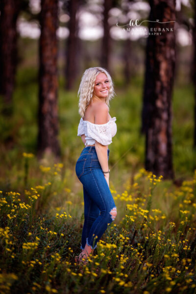 Destin senior photographer captures blonde senior in white off-shoulder top in yellow wildflower field