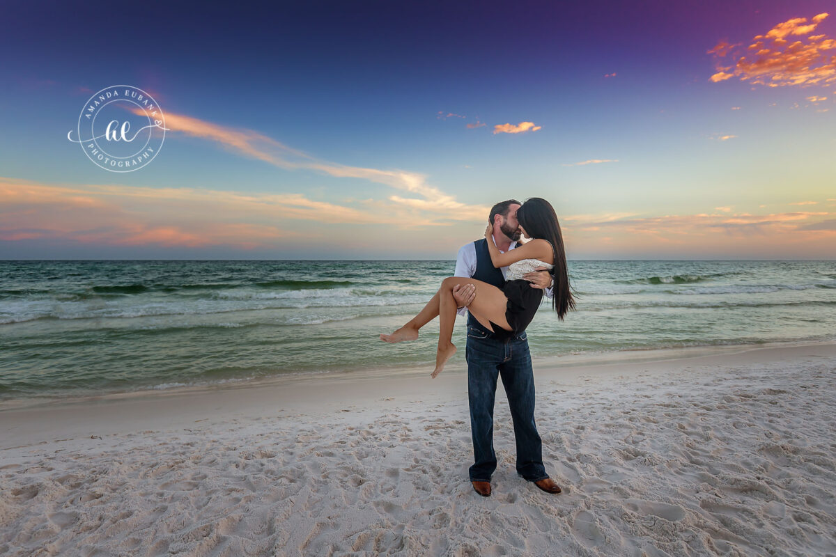Destin engagement photographer captures groom carrying bride-to-be on the beach at sunset